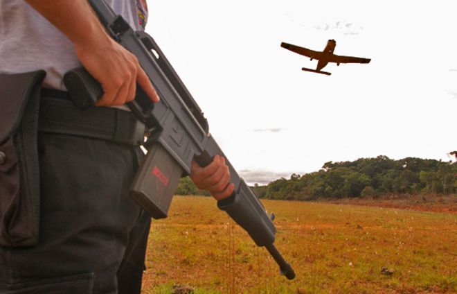 Мужчина держит пистолет, когда самолет летит над головой