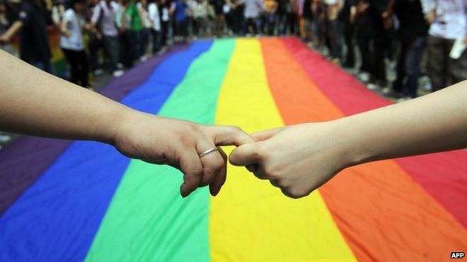 Активисты-геи и лесбиянки образуют человеческую цепь вокруг радужного флага во время празднования в Гонконге 18 мая 2012 года