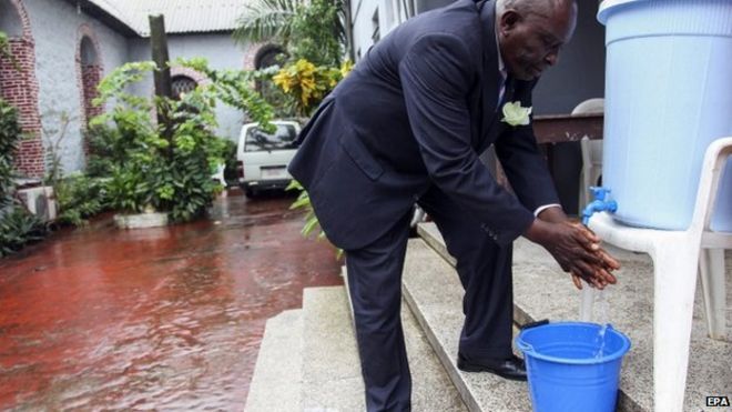 Либерийский мужчина моет руки в качестве дополнительной меры предосторожности для предотвращения распространения вируса Эбола перед началом церковной службы в Монровии, Либерия, 27 июля 2014 года