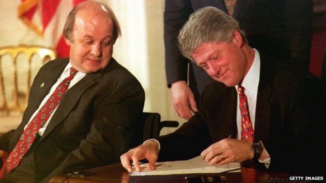 Джеймс Брэди (слева), пресс-секретарь администрации Рейгана, наблюдает, как президент США Билл Клинтон подписывает законопроект Брейди в Белом доме 30 ноября 1993 г.