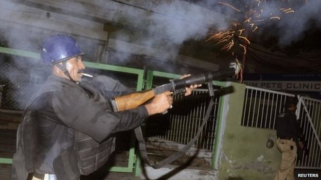 Полицейский стреляет слезоточивым газом, чтобы разогнать сторонников Тахирула Кадри в Лахоре 8 августа 2014 г.