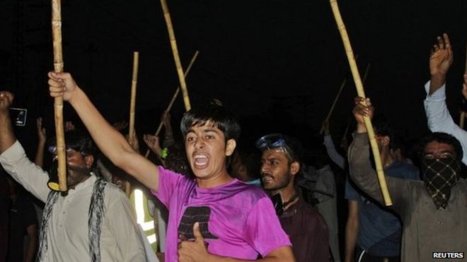 Сторонники Тахирула Кадри, лидера политической партии Пакистан Авами Техрик (ПАТ), выкрикивают лозунги, когда они машут палками во время акции протеста в Лахоре 8 августа 2014 г.