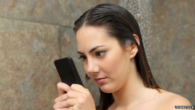Женщина проверяет телефон в душе