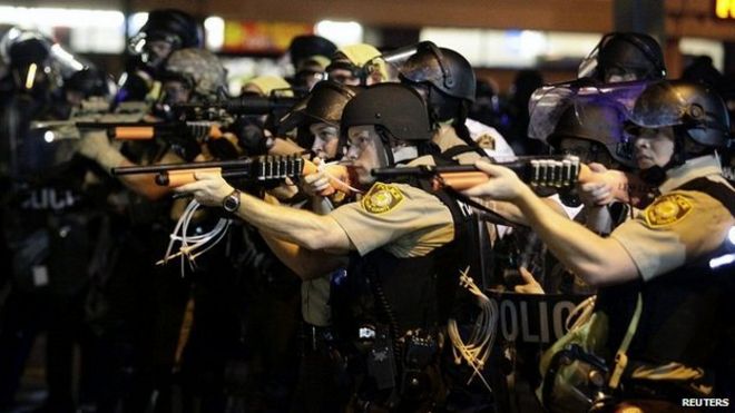 Полицейские направляют оружие на демонстрантов, протестующих против расстрелянной смерти Майкла Брауна в Фергюсоне, штат Миссури, 18 августа 2014 года