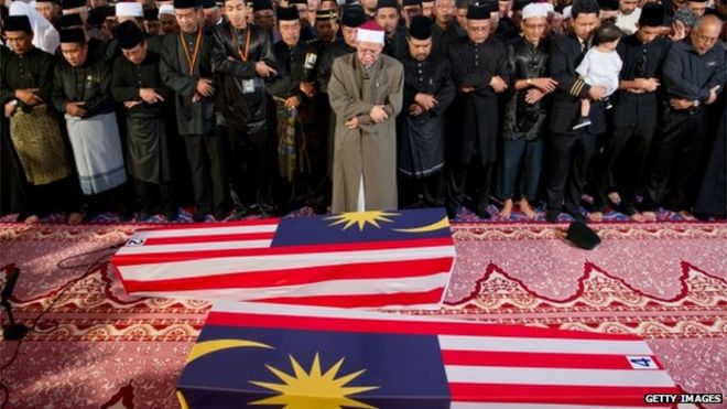 Малайзийские мусульмане и члены их семей возносят особые молитвы за останки второго пилота Ахмада Хакими Ханапи (слева) и стюардессы Нур Шазана Мохамеда Саллеха (справа), погибшего малазийца на борту рейса MH17, который был сбит на востоке Украины в мечети в Путраджайе за пределами Куала-Лумпура 22 августа 2014 года