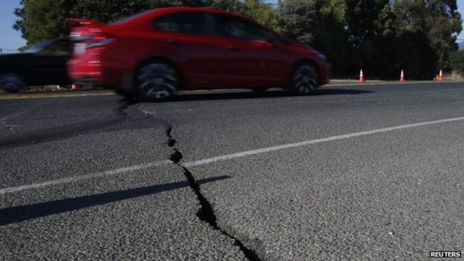 Автомобиль едет по треснувшему асфальту вдоль шоссе 12 после землетрясения силой 6 баллов в Напе, штат Калифорния (24 августа 2014 года)