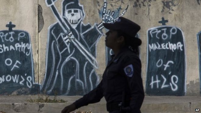 Полицейский проходит мимо граффити с бандитами, изображающими смерть членов банды. 14 апреля 2014