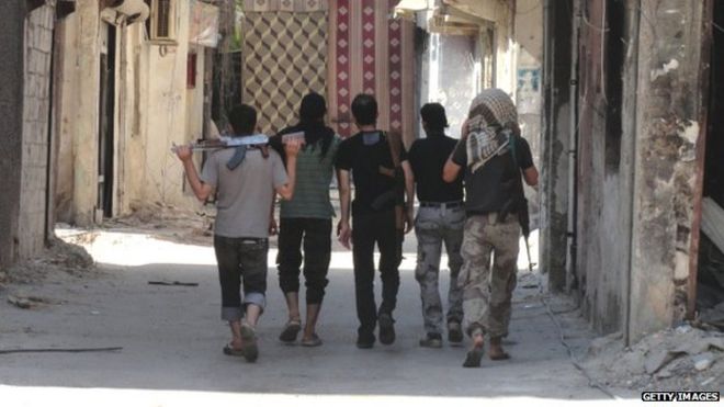 Мятежные бойцы идут со своим оружием, чтобы занять позицию на линии фронта в удерживаемом повстанцами пригороде Дамаска