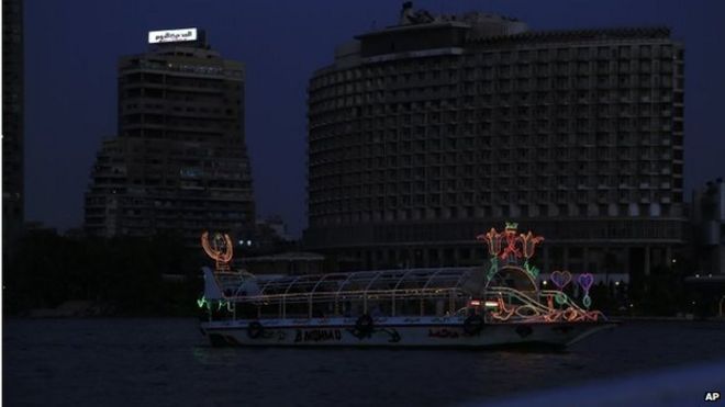 Лодка плывет вдоль реки Нил, а район Гарден-Сити, на заднем плане, остается в темноте во время отключения электроэнергии, Каир, Египет, 5 сентября 2014 года