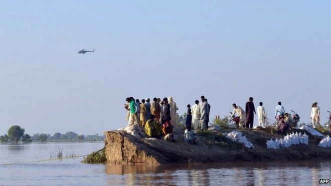 Пакистанские сельские жители собираются на возвышенности, когда 8 сентября 2014 года в районе Хафизабад в провинции Пенджаб идут паводковые воды.