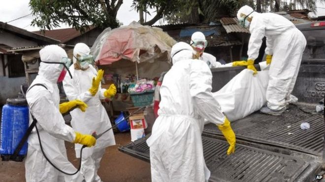 Медицинские работники несут тело женщины, предположительно скончавшейся от лихорадки Эбола в городе Клара, Монровия (10 сентября 2014 года)