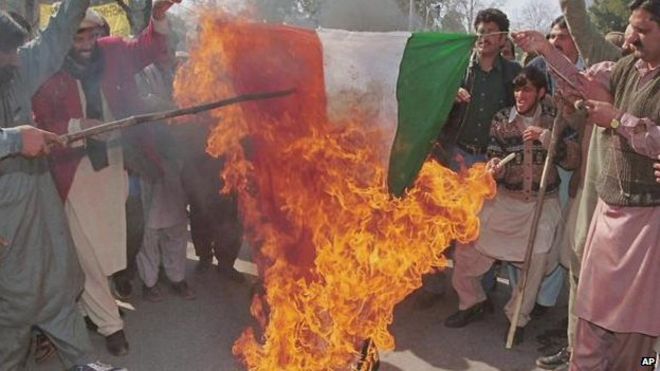 Группа сторонников Кашмира приветствует тот факт, что национальный флаг Индии сожжен во время небольшого митинга в честь дня солидарности у Верховного комиссара Индии в Исламабаде в субботу 5 февраля 2000 года.