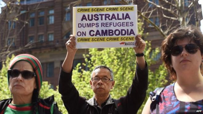 Протестующий держит плакат на митинге в Сиднее 26 сентября 2014 года, выступая против плана Австралии начать отправку просителей убежища в Камбоджу до конца года.