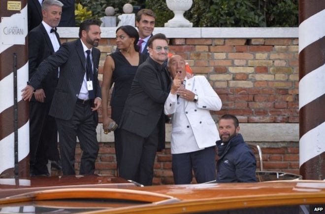 Боно (в темных очках) шутит с консьержем, когда он садится на лодку такси в Венеции, 27 сентября