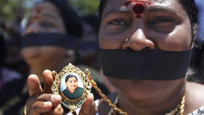 Сторонник демонстрирует кулон с изображением Джаярама Джаялалиты в знак протеста против заключения в тюрьму их лидера в Ченнае, Индия, в воскресенье, 28 сентября 2014 г.