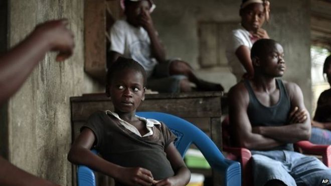 Кумба Файя, 11 лет, сидит с родственниками в своем доме на мосту Святого Павла в Монровии, Либерия. Она потеряла обоих родителей и свою сестру и выздоровела от вируса Эбола и теперь живет со своей большой семьей
