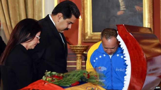 Президент Венесуэлы Николас Мадуро (С), Первая леди Силия Флорес (слева) и Председатель Национального собрания Диосдадо Кабелло (справа) стоят перед гробом Робертом Серра во время похорон в Каракасе (2 октября 2014 года)