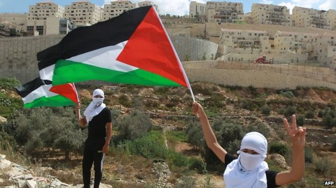 Палестинские демонстранты машут национальным флагом перед израильским поселением Бейтар-Иллит. 26 сентября 2014
