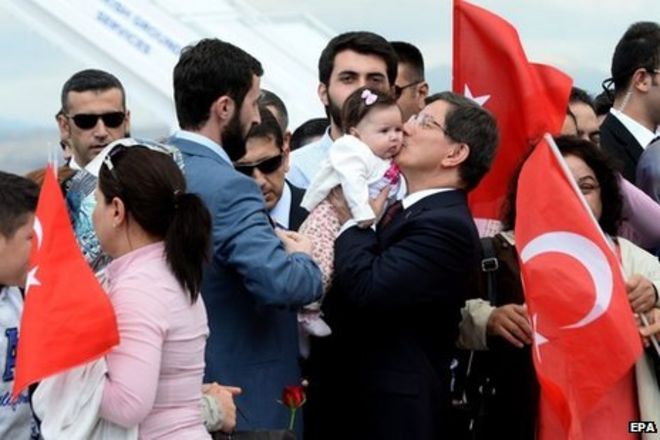 Премьер-министр Турции Ахмет Давутоглу (справа) приветствовал заложников по прибытии в Анкару