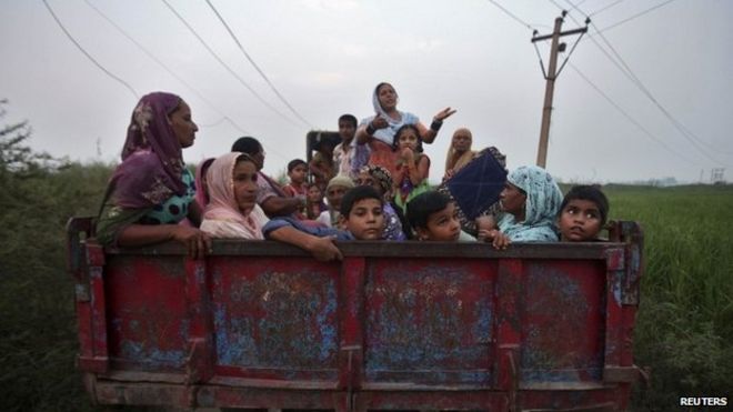 Индийские сельские жители сидят в тракторной тележке, когда они переезжают в более безопасные места в деревне Деви Гарх около Джамму 7 октября 2014 года.