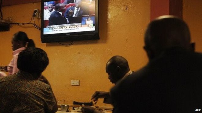 Постоянные клиенты едят в ресторане в Найроби 5 сентября 2013 года, когда местное телевидение транслирует в прямом эфире слушания в парламенте по вопросу о выходе из Международного уголовного суда (МУС)