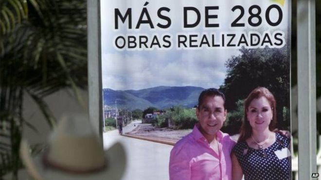 Мужчина просматривает вывеску, рекламирующую городские проекты с участием мэра города и его жены Хосе Луиса Абарки и Марии де лос Анжелес Пинеды Вилла, возле муниципальной штаб-квартиры в Игуале 7 октября 2014 года.