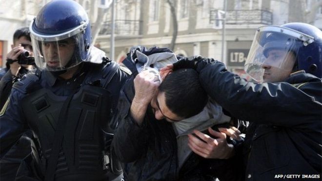 Двое полицейских уводят протестующего в Баку в Азербайджане
