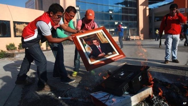 Студенты сжигают портрет губернатора штата Герреро Анхеля Агирре перед тем, как поджечь здание столицы штата в Чильпансинго, Мексика - 13 октября 2014 года