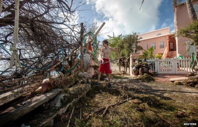 Стефано Аусенда сгребает мусор со своей дороги после того, как ураган Гонсало прошел в округе Сандис, западный Бермудские острова, 18 октября 2014 года