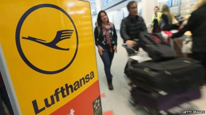 Пассажиры, идущие мимо знака Lufthansa