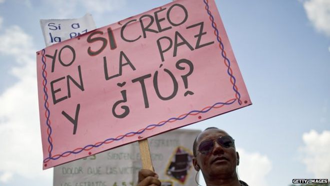 Колумбийский мужчина держит табличку с надписью «Я верю в мир, а вы?» 9 апреля 2014 года.