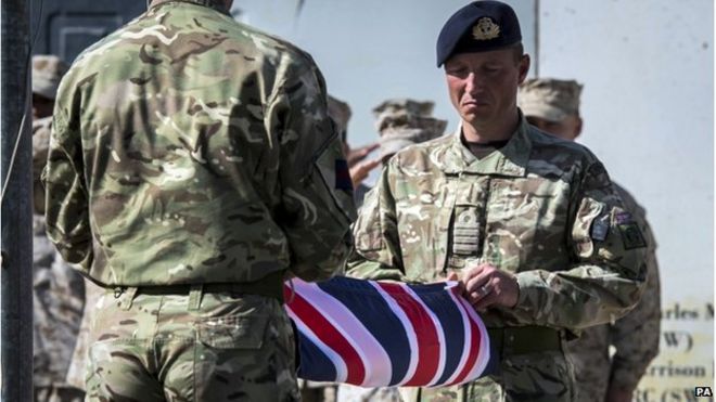 Два британских солдата держат свернутый британский флаг
