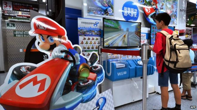 Клиенты играют с игровой консолью Nintendo Wii U в магазине электроники в Токио.