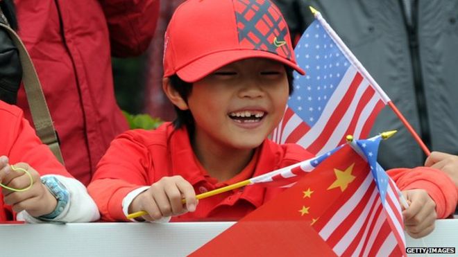 Китайский мальчик размахивает флагами Китая и США