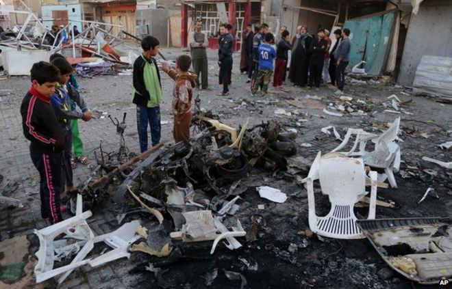 Гражданские лица осматривают последствия взрыва автомобильной бомбы в городе Садр, Багдад, Ирак. Воскресенье, 9 ноября 2014 г.