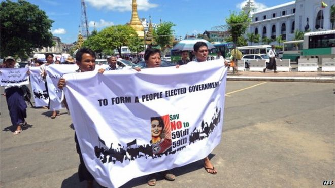 Группа протестующих держат плакаты во время акции протеста, призывающей внести поправки в конституцию Мьянмы в центре Янгона 27 мая 2014 года.