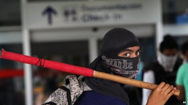 Студент в маске держит палку во время акции протеста против исчезновения 43 студентов в аэропорту Акапулько 10 ноября 2014 года.