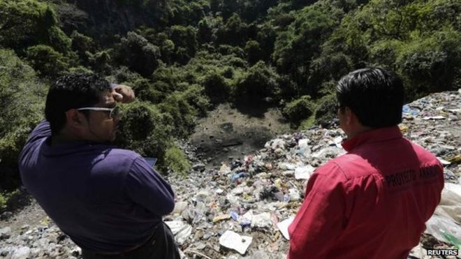 Люди наблюдают за мусорной свалкой, где 8 ноября 2014 года возле горного городка Кокула в штате Герреро были найдены останки.