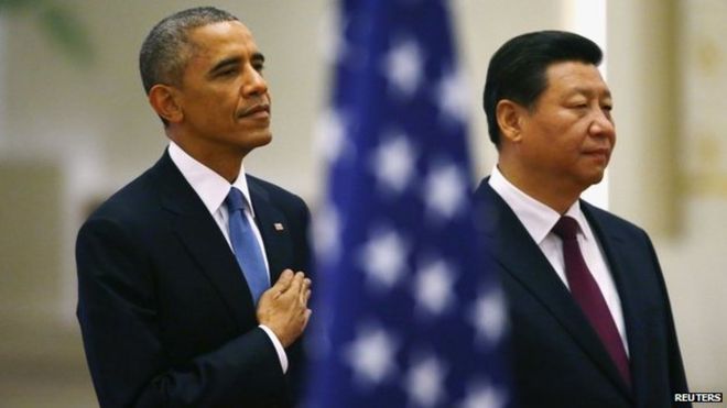 Президент США Барак Обама (слева) и президент Китая Си Цзиньпин слушают государственные гимны под флагом США во время церемонии встречи в Большом зале народных собраний в Пекине, 12 ноября 2014 года