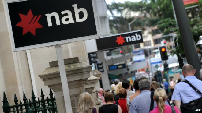 Люди проходят мимо табличек Национального австралийского банка, украшающих здание в центре Брисбена - 5 декабря 2011 года