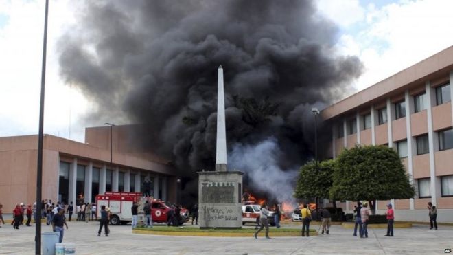 Пожарные прибывают, чтобы попытаться потушить несколько горящих автомобилей перед государственным конгрессом в Чильпансинго 12 ноября 2014 года.