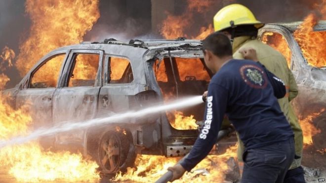 Пожарные пытаются потушить пожар на автомобилях, подожженных демонстрантами в Чильпансинго 12 ноября 2014 года