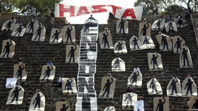 Активисты держат нарисованные силуэты, представляющие 43 пропавших студентов, во время выполнения символической блокады пирамиды в месте археологических раскопок Монте-Альбана в Оахаке 12 ноября 2014 года