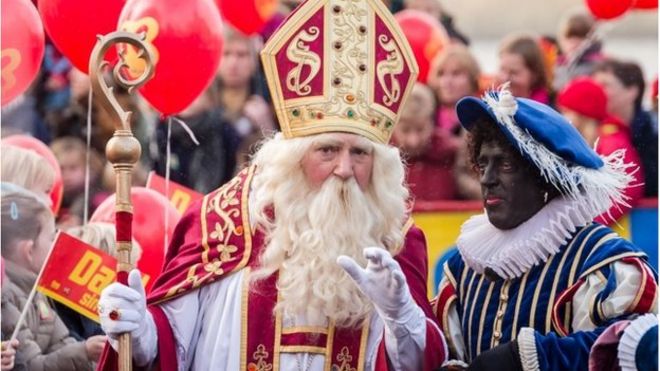 Актеры в костюме Святого Николая (слева) и Черный Пит приветствуют детей в Антверпене, Бельгия, в субботу 15 ноября