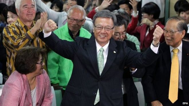 Такеши Онага (в центре) исполняет танец в честь своей победы на выборах губернатора Окинавы в Наха, южный остров Окинава, Япония, 16 ноября 2014 года