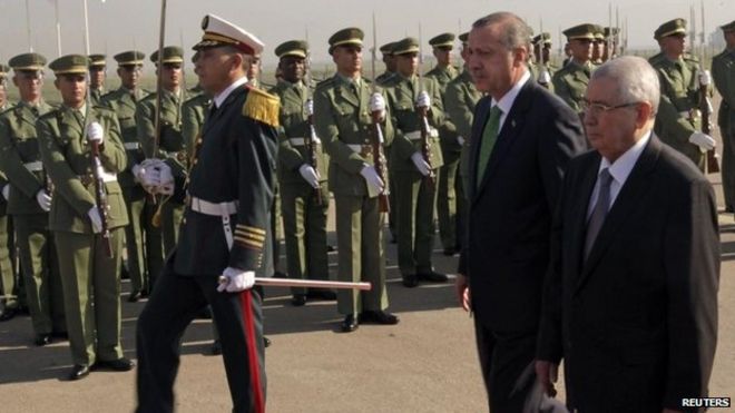 Президент Турции Реджеп Тайип Эрдоган (в центре) осматривает почетный караул во время церемонии приветствия по прибытии в аэропорт Алжира (19 ноября 2014 года)