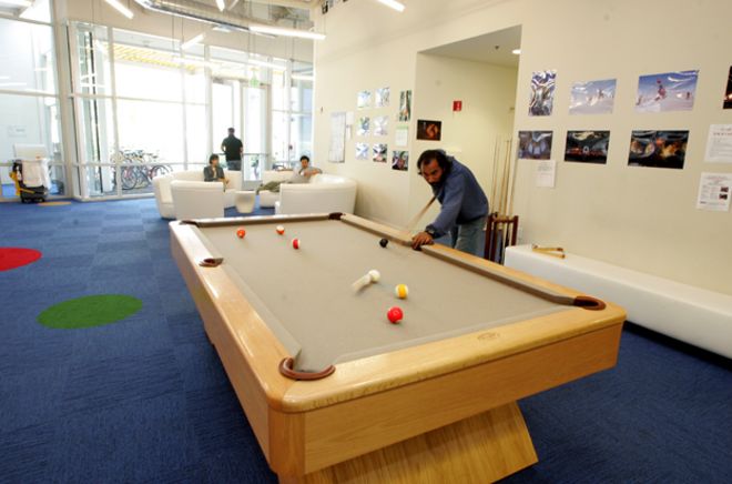 Человек играет в бильярд в офисах Google