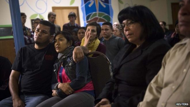 Иммигрант без документов Анджела Наварро и ее муж Эрмер Фернандес (слева) вместе с другими иммигрантами и сторонниками наблюдают за выступлением президента США Барака Обамы 20 ноября 2014 года