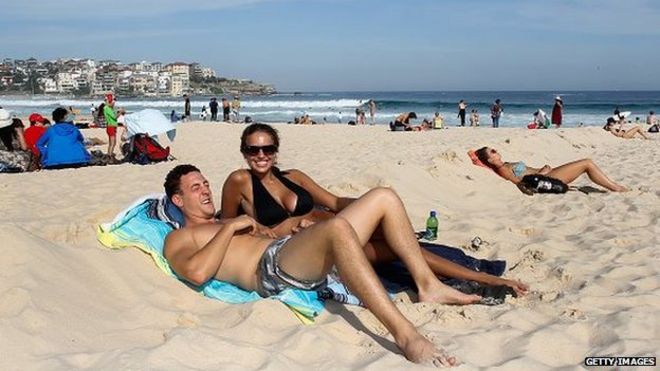 Пара наслаждается солнцем на пляже Бонди в Австралии
