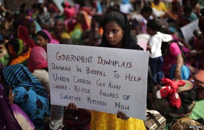 Ребенок жертвы газовой трагедии в Бхопале, утечки газа с завода по производству пестицидов Union Carbide, в результате которого погибли по меньшей мере 3500 человек, держит плакат во время сидячей акции протеста в Нью-Дели 10 ноября 2014 года.